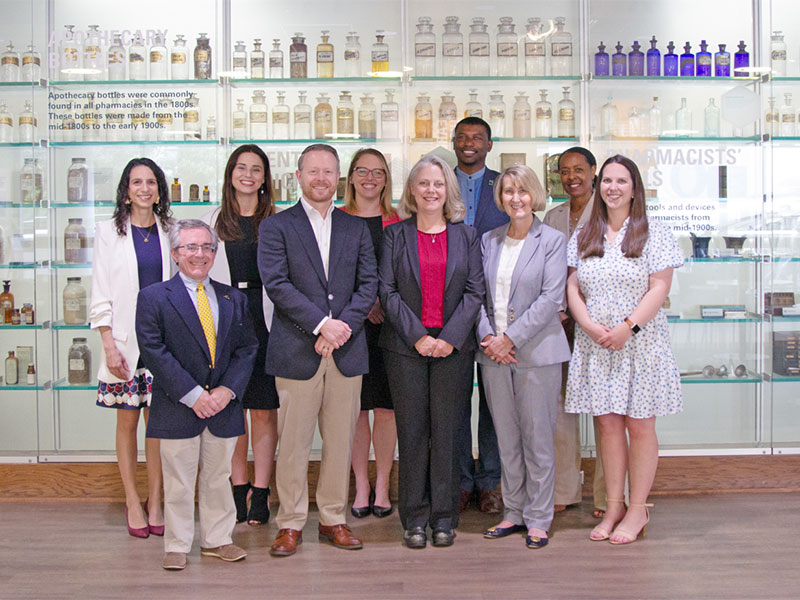 v c u school of pharmacy community pharmacists stand in front of showcase with pharmacy tools.