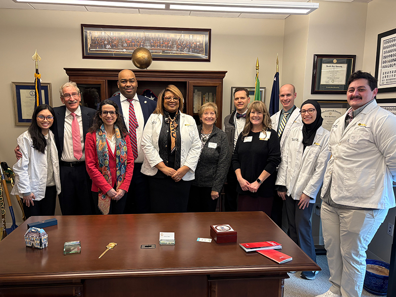 c p p i director, Teresa Salgado stands with a group legislators behind a desk