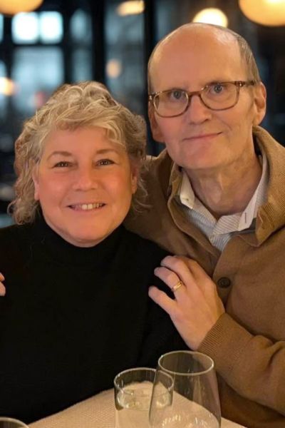 David and Diane Holdford sit close together smiling at the camera in a booth at a restaurant