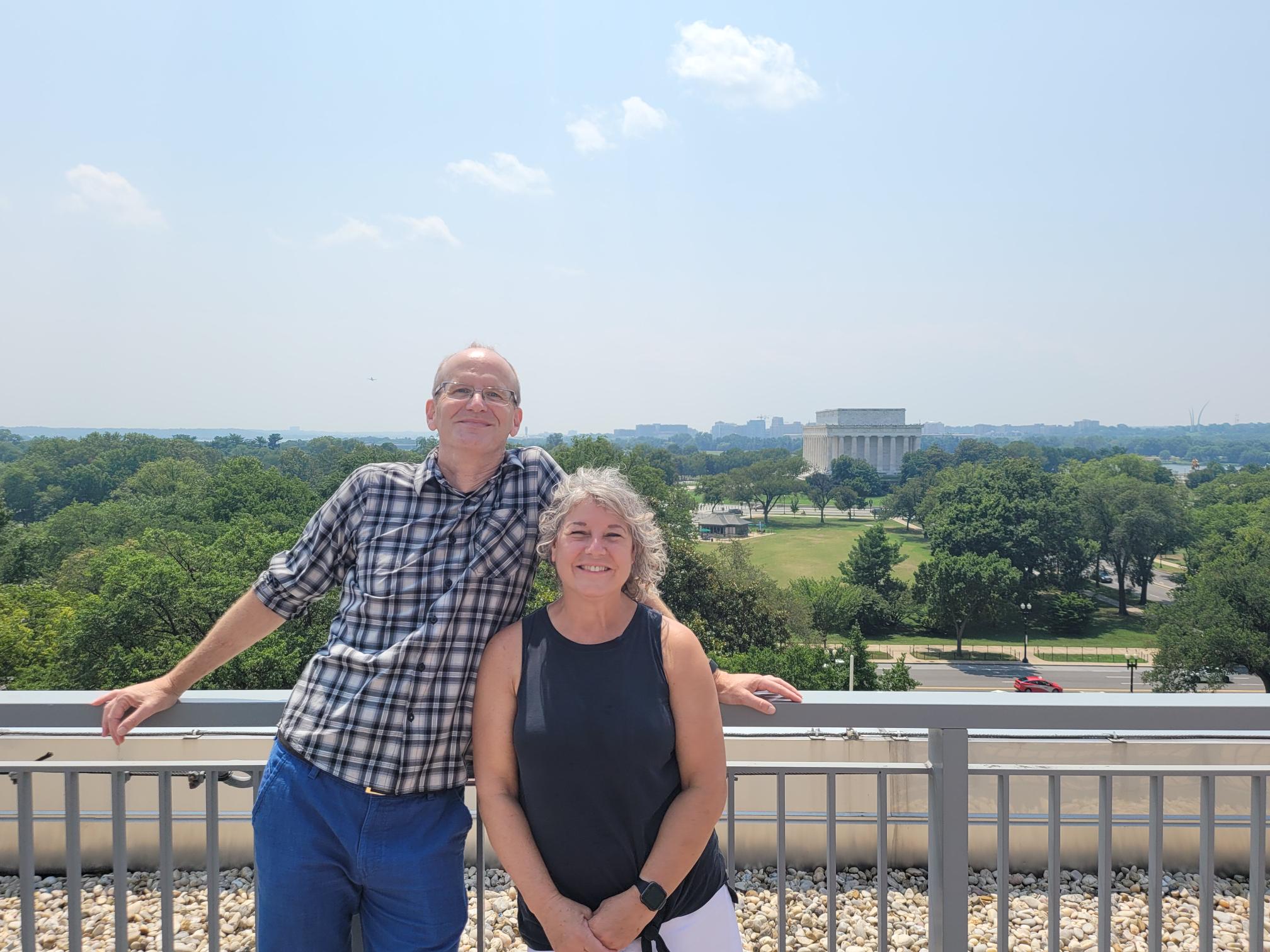 David and Diane Holdford stand side by side smiling on a balcony in Washington, D.C., at the APhA Headquarters